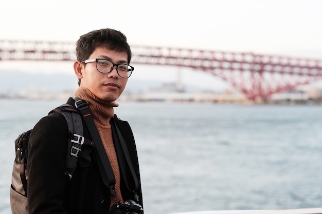 Felice l'uomo in cappotto e macchina fotografica, il viaggiatore asiatico gode e la vista panoramica sulla nave