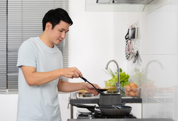 自宅のキッチンで料理と料理を準備する幸せな男