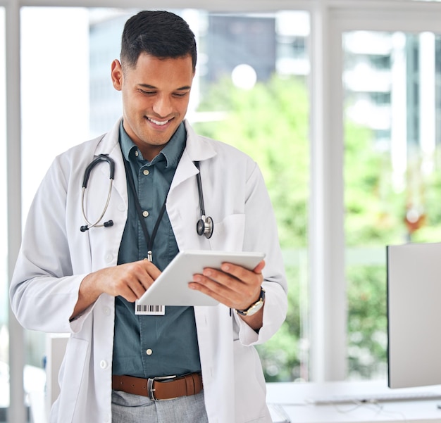 Happy man doctor and tablet in medical research for innovation networking or Telehealth at hospital Male person or healthcare professional smile on technology for online communication or browsing