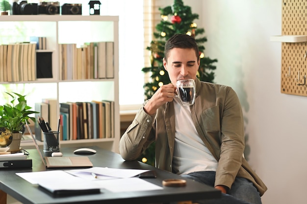 Happy man drinking coffee while sitting in home office.
