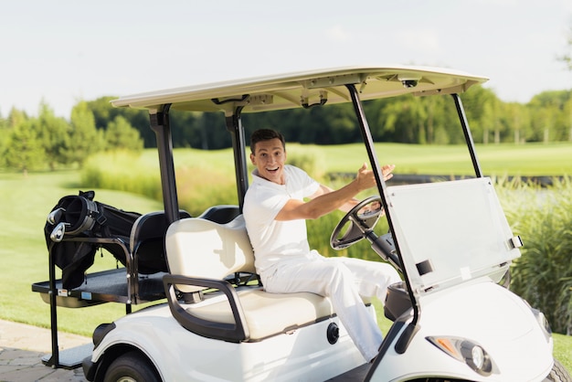 L'uomo felice guida il golfista dell'automobile di golf su un corso.