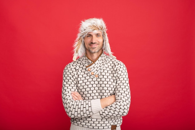 Photo happy man in earflap hat grizzled guy in sweater on red background hoary man wear warm hat