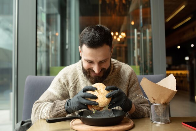 Happy man eating burger in restaurant