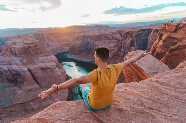 Happy man on the edge of the cliff Horseshoe Bend Canyon in Page Arizona Adventure and tourism concept