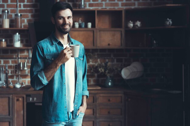 Happy man enjoying his coffee during a break in the kitchen.