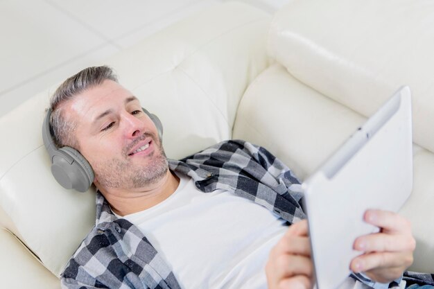 Foto uomo felice che si gode la musica con un tablet sul divano