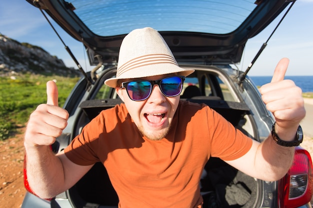 Happy man enjoying road trip and summer vacation. Travel, holidays and people concept