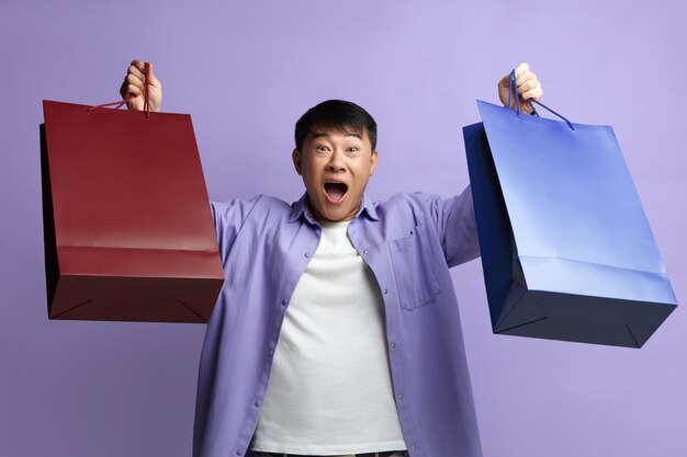 Photo happy man enjoying shopping satisfied guy holding and showing shopping bags