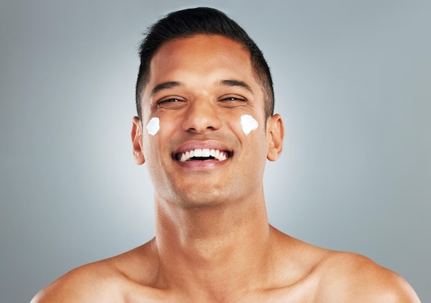 Happy man face cream skincare and portrait moisturizer healthy aesthetic and glowing skin on grey studio background Smile headshot male model or facial dermatology product cosmetics and wellness