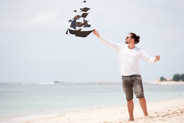 Happy man flying kite coast ocean