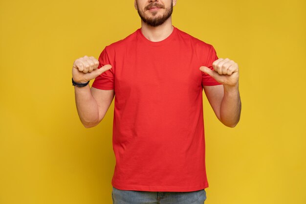 黄色の壁に隔離された赤いTシャツとキャップの配達サービスから幸せな男