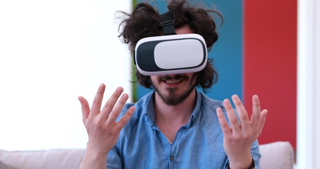 happy man getting experience using VR-headset glasses of virtual reality at home