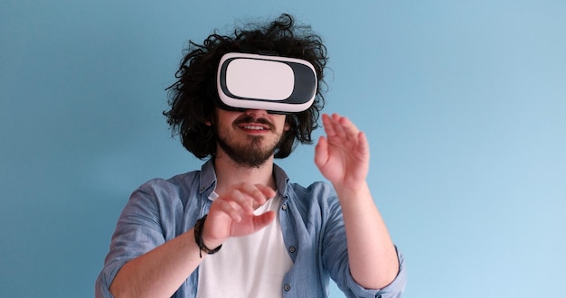 Счастливый человек получает опыт использования гарнитуры VR в очках виртуальной реальности, изолированных на синем фоне