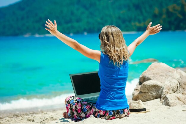 Счастливая девушка с ноутбуком возле моря на выходных