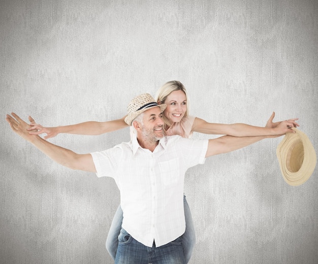 Photo happy man giving his partner a piggy back against weathered surface