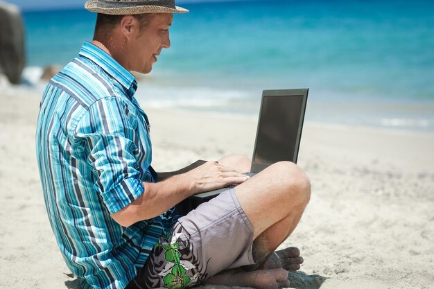 A Happy man guy with laptop near the seashore weekend travel