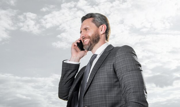 Photo happy man has phone talk wear suit photo of man has phone talk man has phone talk on sky background man has phone talk outdoor