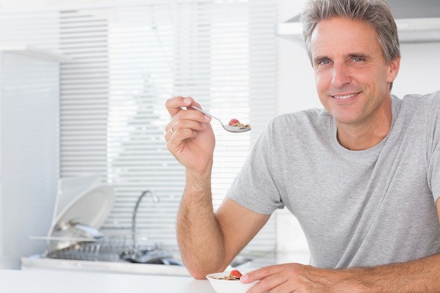 キッチンで朝食の穀物を持っている幸せな男