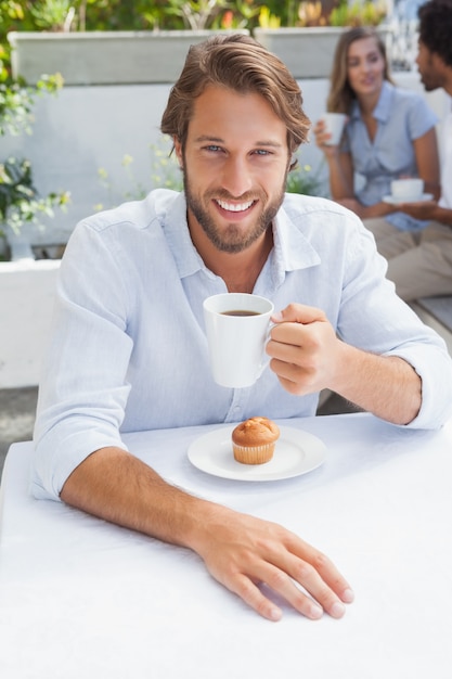 コーヒーとマフィンを持つ幸せな男