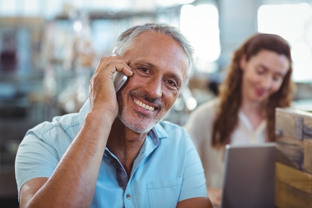 Foto uomo felice che ha telefonata e che sorride alla macchina fotografica