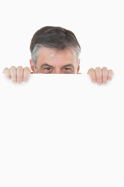 Happy man hiding behind white board