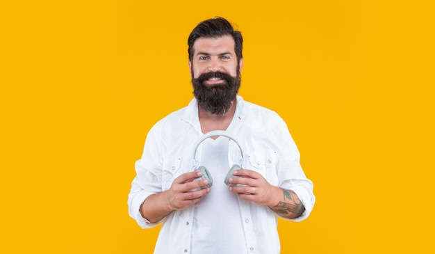 Happy man hipster listen ebook in headphones isolated on yellow background ebook in headphones