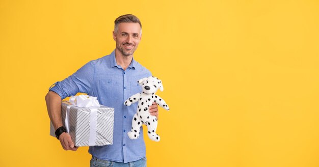 Happy man hold present box and toy on yellow background copy space purchase