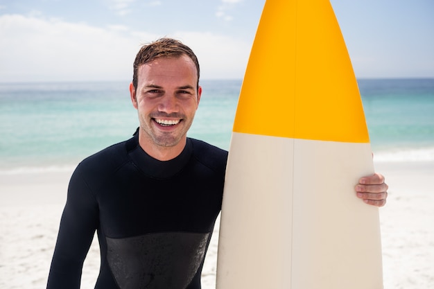 Фото Счастливый человек, держащий доску для серфинга на пляже