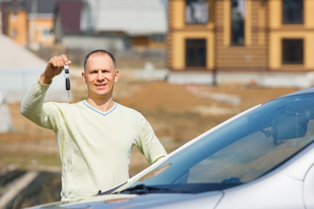 Happy man holding car keys on the background of the house