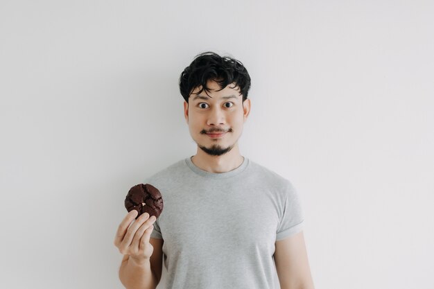 白い背景で隔離のチョコレートクッキーを保持している幸せな男