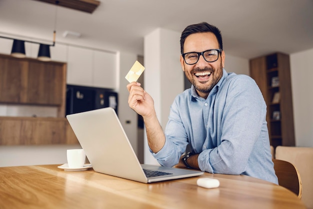 A happy man holding credit card and showing it at the camera