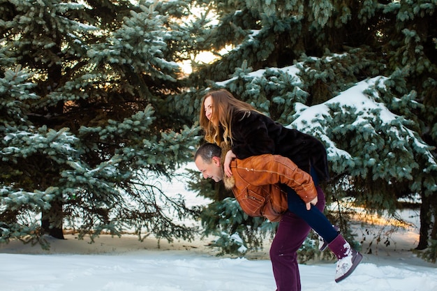 Фото Счастливый мужчина держит жену на руках в зимнем парке с днем святого валентина зимние каникулы