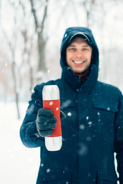 Happy man holding thermos in winter park