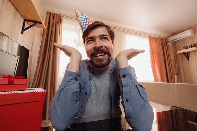 The happy man in the holiday cap is chatting with friends or parents via video chat