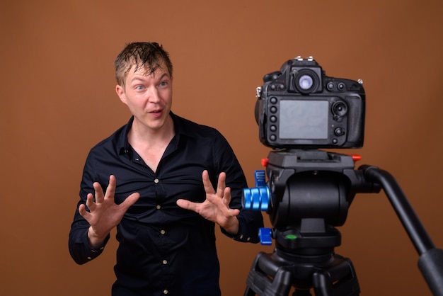 Happy man influencer vlogging with DSLR camera 