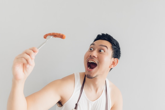 幸せな男は彼が彼自身を調理したおいしい好きなソーセージを食べています。