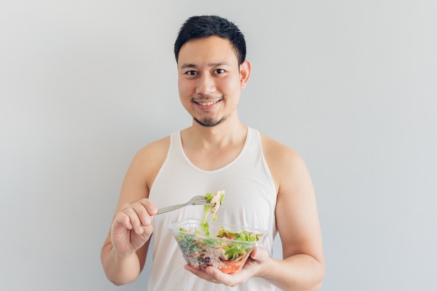 L'uomo felice sta mangiando il pasto sano dell'insalata.