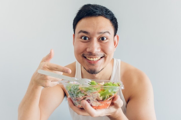 幸せな男は健康的なサラダの食事を提示しています。