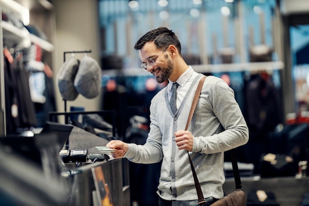 A happy man is purchasing with credit card in boutique