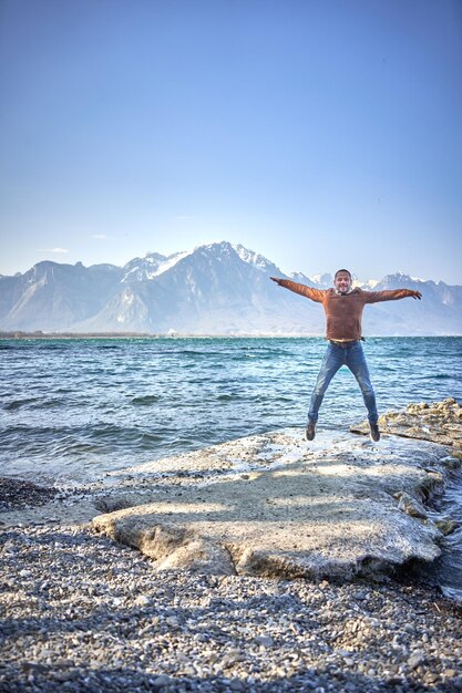 幸せな男はスイスの湖で空中にジャンプします