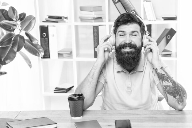 Foto uomo felice che ascolta la melodia in cuffia nella musica d'ufficio