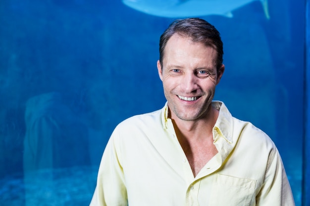 Happy man looking at camera beside the fish tank