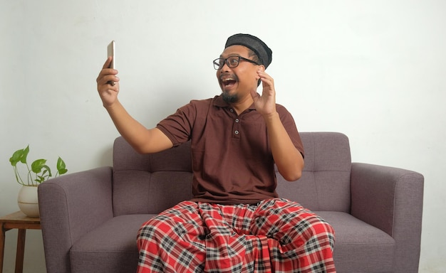 Happy man looking phone screen in sofa