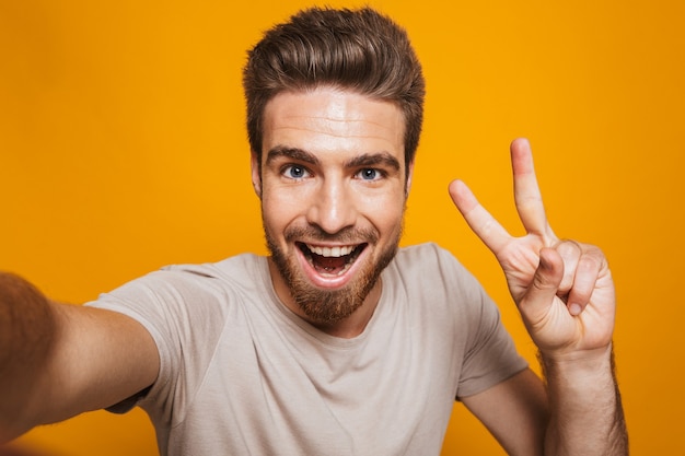 Happy man make a selfie by camera with peace gesture.