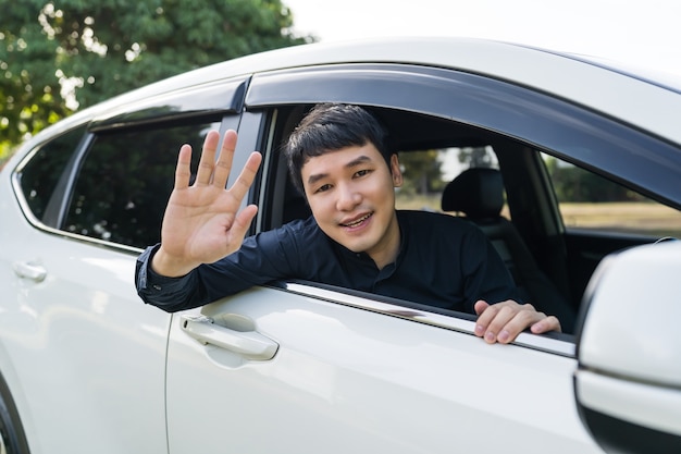 happy man open window of a car and raising his hand