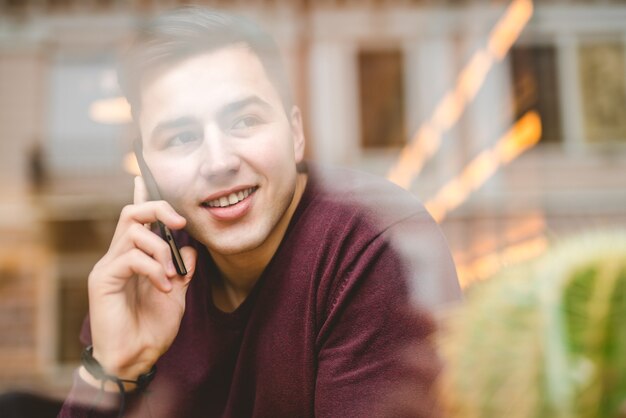 Photo the happy man phone over the window