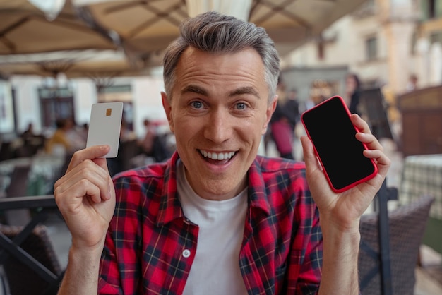 Happy man in plaid shirt holding a sim card and a phone