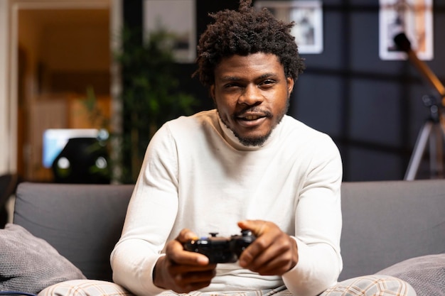 happy man playing shooter videogame in warm apartment holding controller