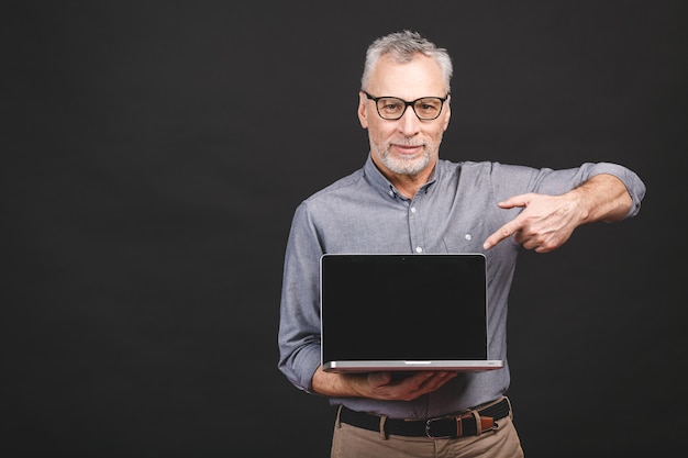 Happy man pointing up at copy space while holding laptop with blank screen. 