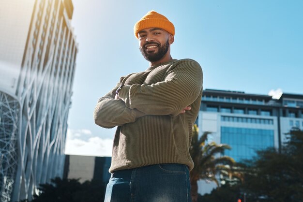 Happy man and portrait with arms crossed in city to travel or commute to university in urban cbd or town campus College student or confident person smile or relax outdoor in street with buildings